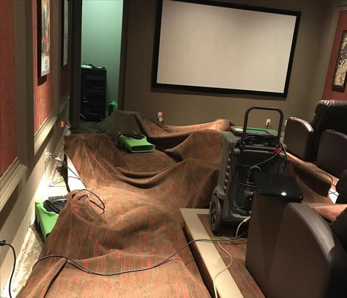 Entertaining Area With Movie Seating Flooded Affecting The Carpets In The Room. SERVPRO Equipment In Use On Floors.