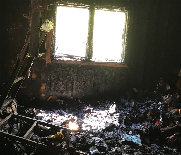 Living room that has been burned in a house fire with black soot on walls and on belongings.