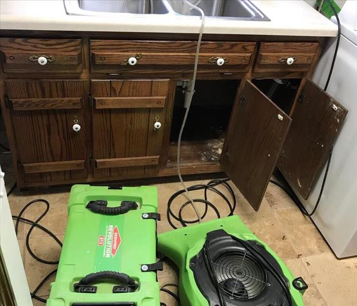 SERVPRO equipment sitting in customer's bathroom pointing at the leaky pipes under the cabinet.