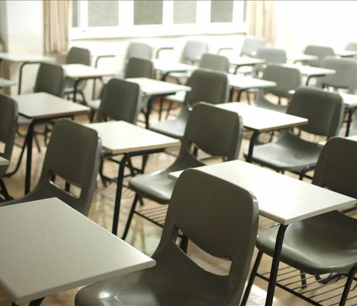 Rows of empty school desks sitting in an empty classroom.